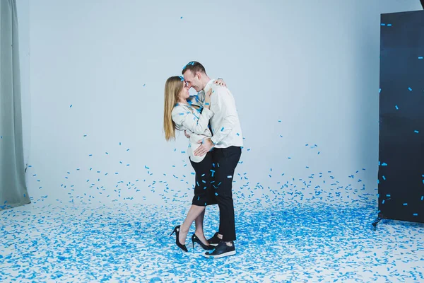 stock image Young happy married couple hugging in blue confetti. A couple in love rejoices and has fun. Gender photo session