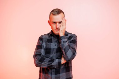 Pembe arka planda kareli gömlekli, gülümseyen genç bir adam. Metin için yer