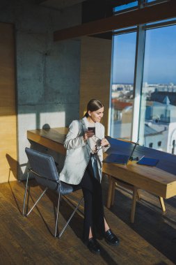 Ofis işleri, ofiste çalışan çekici genç bayan yöneticiler modern dizüstü bilgisayarla parlak çalışma alanları, lezzetli kahve içen genç kadınlar.