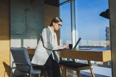 Ofis işleri, ofiste çalışan çekici genç bayan yöneticiler modern dizüstü bilgisayarla parlak çalışma alanları, lezzetli kahve içen genç kadınlar.