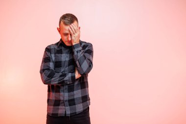 Pembe arka planda kareli gömlekli, gülümseyen genç bir adam. Metin için yer