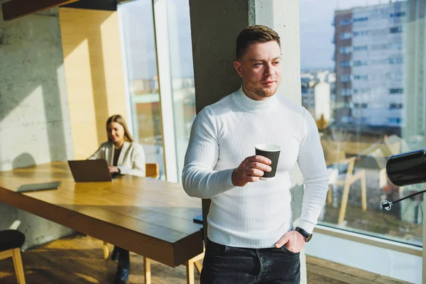 프리랜서는 공간에 원격으로 일하면서 커피를 마십니다 스웨터를 바지를 사무실에서 행복하게 — 스톡 사진