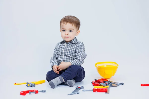 stock image A little boy in a shirt with a helmet and a toy tool. White background. Toy construction tool for children