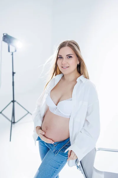 白地にブラジャーとホワイトのシャツを着た可愛い妊婦さん 幸せな妊娠中の女性ストローク彼女の腹 — ストック写真