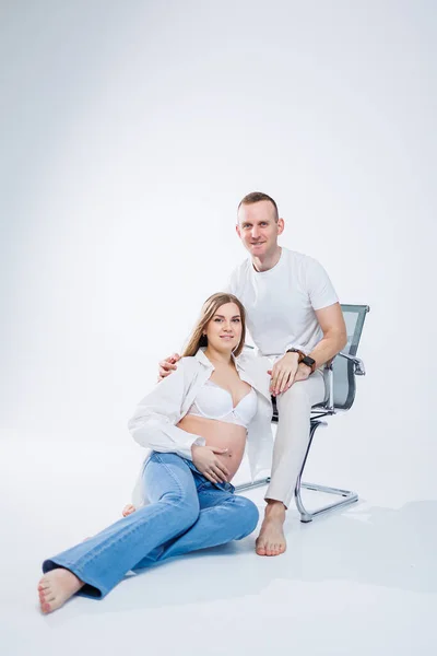 一个孕妇和一个男人站在一个白色的背景上 漂亮的年轻漂亮的孕妇 分娩概念 快乐的怀孕夫妇 — 图库照片