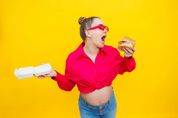 Голодна Вагітна Жінка Тримає Гамбургер Їсть Нездорову Їжу Позуючи Жовтому — стокове фото