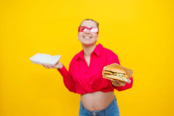 Голодна Вагітна Жінка Тримає Гамбургер Їсть Нездорову Їжу Позуючи Жовтому — стокове фото