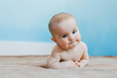 Küçük şirin bebek karnının üstünde yatar ve başını tutar, çocuk gelişimi.