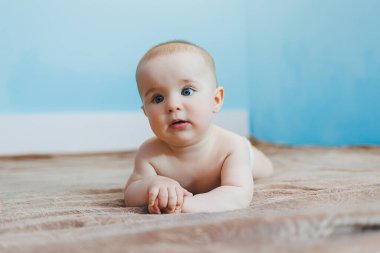 Küçük şirin bebek karnının üstünde yatar ve başını tutar, çocuk gelişimi.