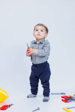 Beyaz arka planda, bir müteahhit kılığında tişörtlü şirin bir çocuk. Çocukluk, öğrenme, çalışma, oyunlar, kariyer, taklit. Küçük babanın yardımcısı..