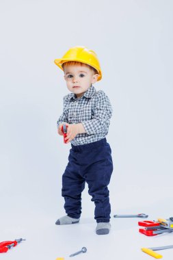 Beyaz arka planda, bir müteahhit kılığında tişörtlü şirin bir çocuk. Çocukluk, öğrenme, çalışma, oyunlar, kariyer, taklit. Küçük babanın yardımcısı..