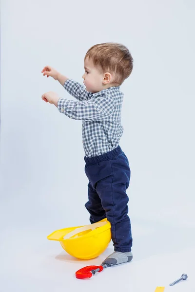 stock image A little boy in a shirt with a helmet and a toy tool. White background. Toy construction tool for children