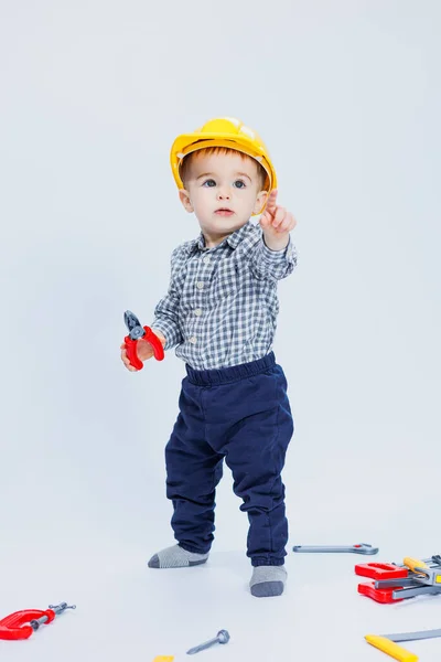 A cute boy in a shirt in the image of a builder, on a white background. Childhood, learning, work, games, career, imitation. Little daddy\'s helper.