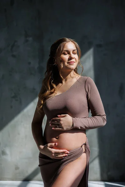 Kahverengi Narin Takım Elbiseli Mutlu Hamile Bir Kadın Karnını Okşayıp — Stok fotoğraf