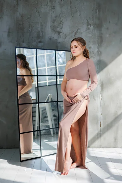 スカートの中の妊婦は手で胃を抱きしめる 妊娠中のファッション女性 灰色の背景の完全な長さの肖像画 幸せな妊娠 — ストック写真