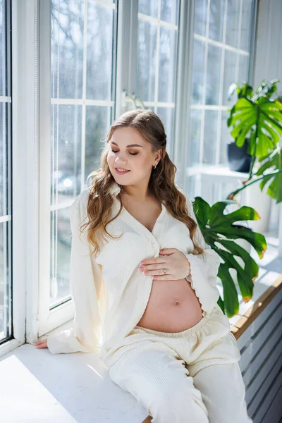 Μια Ελκυστική Νεαρή Έγκυος Γυναίκα Ελαφρύ Λευκό Κοστούμι Κάθεται Στο — Φωτογραφία Αρχείου