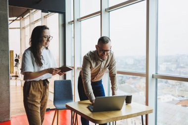 Tatmin olmuş genç bir adam bayan bir meslektaşıyla konuşur ve yapılan işten memnun kalır. Meslektaşlar ofiste dizüstü bilgisayarda çalışır. Modern bir ofis alanında çalışmak.