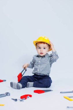 Küçük bir çocuk beyaz bir arka planda bir oyuncak set inşaatçı aletleriyle oynuyor. Çocuk plastik oyuncakları..