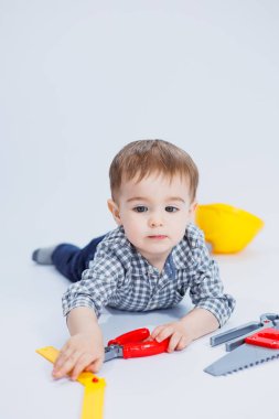 Küçük bir çocuk beyaz bir arka planda bir oyuncak set inşaatçı aletleriyle oynuyor. Çocuk plastik oyuncakları..