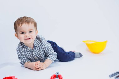 Küçük bir çocuk beyaz bir arka planda bir oyuncak set inşaatçı aletleriyle oynuyor. Çocuk plastik oyuncakları..