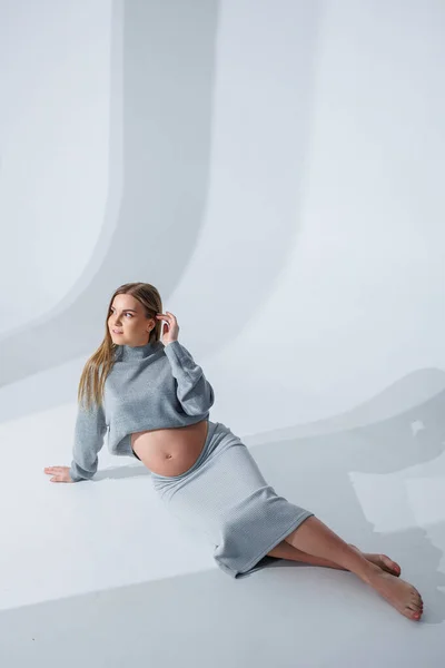 Cute Młoda Kobieta Ciąży Głaskanie Jej Brzuch Siedzi Białym Tle — Zdjęcie stockowe