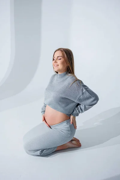 Cute Młoda Kobieta Ciąży Głaskanie Jej Brzuch Siedzi Białym Tle — Zdjęcie stockowe