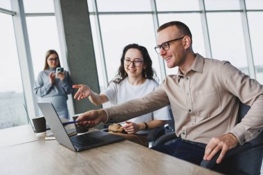 Büyük pencereli bir ofiste çalışmak, meslektaşlar taşınabilir bir dizüstü bilgisayar kullanarak yeni bir proje üzerinde çalışıyorlar. Çalışanlarla modern ofis.