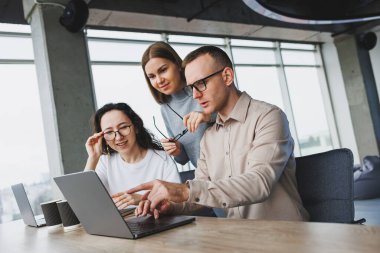 Ofis çalışanları bilgisayarda toplanıyor. Yaratıcı ekip laptopunu ofiste paylaşıyor, başlangıç sunumunu gözden geçiriyor, tasarım projesi, konuşurken fikirleri tartışıyor.