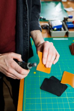 Profesyonel bir zanaatkarın elleri deri bir cüzdan yapar. Yeni, temiz, deri bir cüzdan, yakın plan kesilmiş bir fotoğraf..