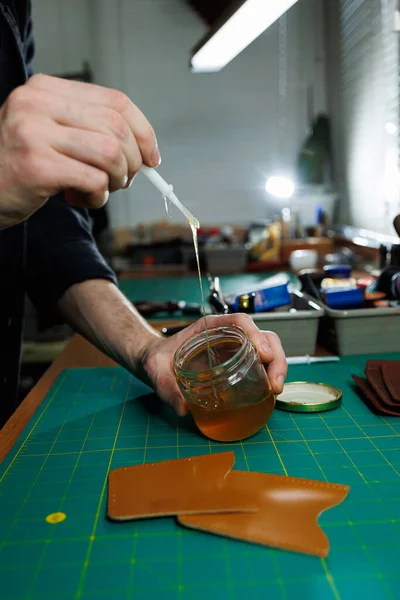 stock image The hands of the master sew handmade leather products. Men's hands connect the parts, creating quality leather accessories. Working process in a leather workshop