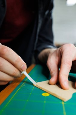 Ustanın elleri el yapımı deri ürünler dikiyor. Erkeklerin elleri parçaları birleştirir, kaliteli deri aksesuarlar yaratır. Deri atölyesinde çalışma süreci