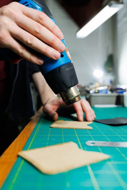 Ustanın elleri el yapımı deri ürünler dikiyor. Erkeklerin elleri parçaları birleştirir, kaliteli deri aksesuarlar yaratır. Deri atölyesinde çalışma süreci