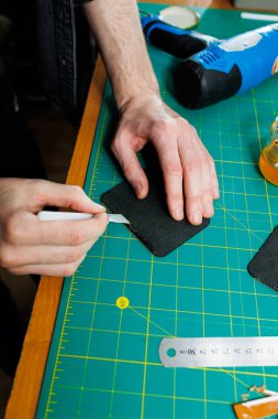 Profesyonel bir zanaatkarın elleri deri bir cüzdan yapar. Yeni, temiz, deri bir cüzdan, yakın plan kesilmiş bir fotoğraf..