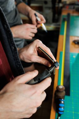 Ustanın elleri el yapımı deri ürünler dikiyor. Erkeklerin elleri parçaları birleştirir, kaliteli deri aksesuarlar yaratır. Deri atölyesinde çalışma süreci