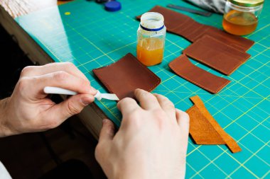 Doğal deriyle çalışan erkek ellerinin yakın çekimi. Gerçek deriden yapılmış el yapımı ürünler..