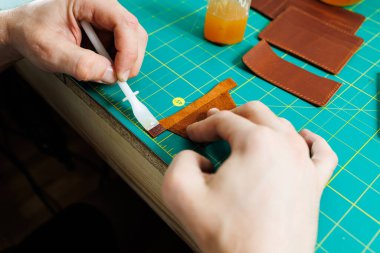 Doğal deriyle çalışan erkek ellerinin yakın çekimi. Gerçek deriden yapılmış el yapımı ürünler..