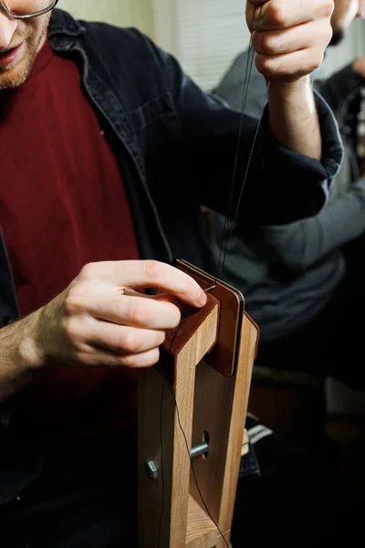 stock image The hands of the master sew handmade leather products. Men's hands connect the parts, creating quality leather accessories. Working process in a leather workshop