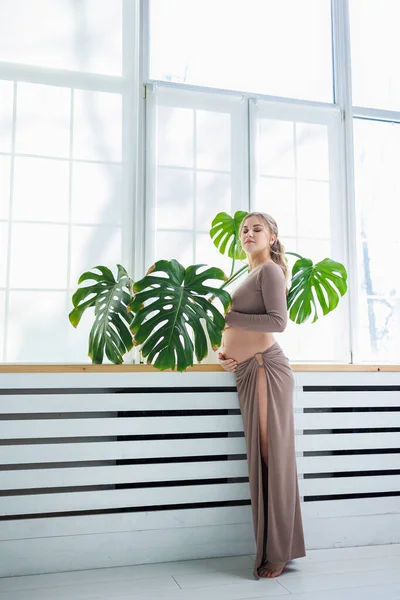 stock image A beautiful pregnant woman in a top and skirt hugs her belly. Stylish pregnant woman