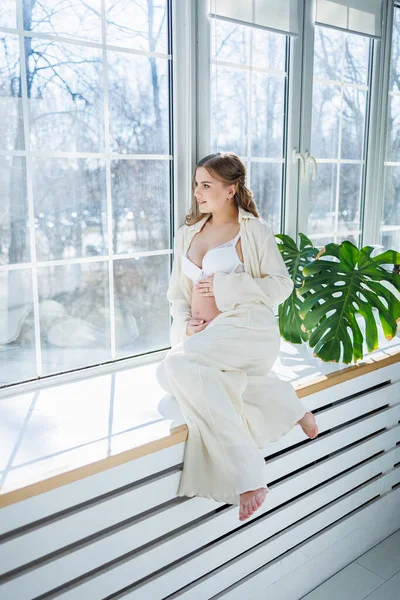 Una Joven Mujer Embarazada Con Estilo Traje Blanco Está Sentado — Foto de Stock