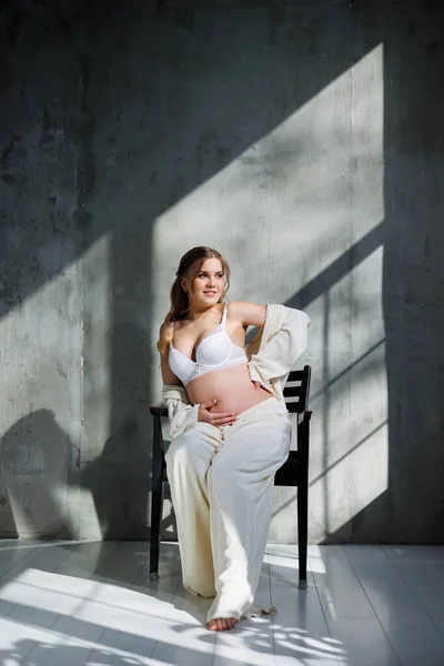 Μια Κομψή Νεαρή Έγκυος Γυναίκα Λευκό Κοστούμι Κάθεται Μια Καρέκλα — Φωτογραφία Αρχείου