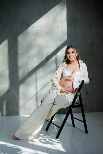 Beyaz Takım Elbiseli Şık Hamile Bir Kadın Sandalyeye Oturur Nazikçe — Stok fotoğraf