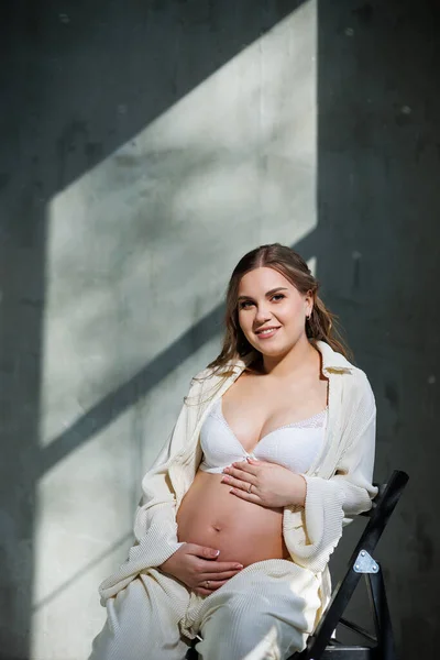 Een Stijlvolle Zwangere Jonge Vrouw Een Wit Pak Zit Een — Stockfoto