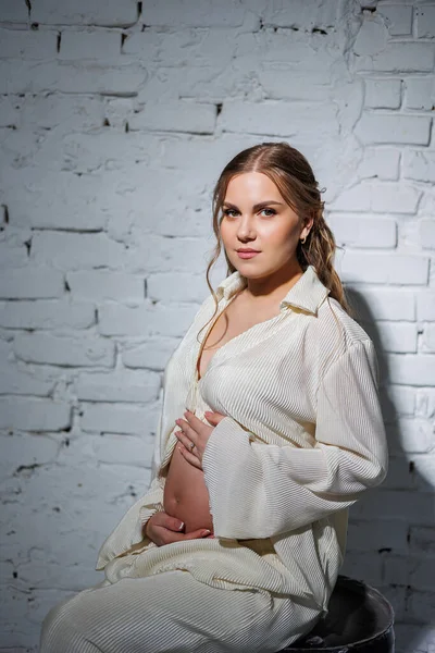 Una Joven Embarazada Con Estilo Traje Blanco Sienta Contra Una — Foto de Stock