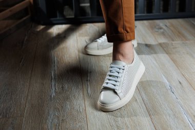 Beyaz deri ayakkabılarla kadın bacaklarının yakın çekimi. Yazlık kadın ayakkabıları koleksiyonu. Bağcıklı beyaz kadın ayakkabıları.