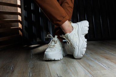 Yüksek tabanlı beyaz deri ayakkabılarla kadın bacaklarının yakın çekimi. Yazlık kadın ayakkabıları koleksiyonu. Bağcıklı beyaz kadın ayakkabıları.