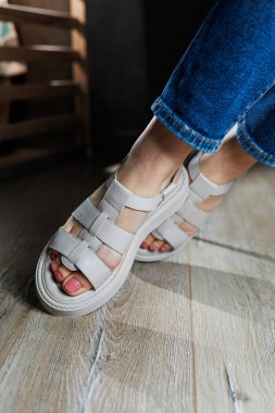 Gri parke üzerinde deri sandaletli güzel, narin kadın bacakları. Kadın sandaleti koleksiyonu