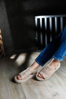 Yaz kadın sandaletleri. Kadın deri sandaletlerinin koleksiyonu. İnce kadın bacakları, topuksuz bej deri sandaletler içinde..