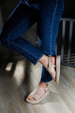Yaz kadın sandaletleri. Kadın deri sandaletlerinin koleksiyonu. İnce kadın bacakları, topuksuz bej deri sandaletler içinde..