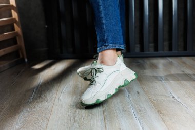 Kot pantolonlu kadın bacaklı beyaz deri spor ayakkabılar. Kadın ayakkabıları işte. Rahat kadın ayakkabıları.