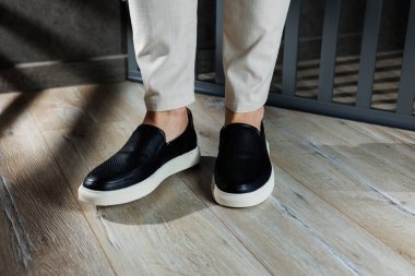 Deri ayakkabılı erkek bacakları. Bağcıksız, rahat siyah ayakkabılar. Sıradan erkek mokasenleri.